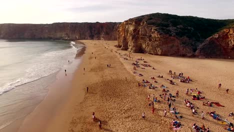 People-rest-on-a-beautiful-sandy-beach-in-Portugal,-Praia-do-Beliche,-Sagres,-aerial-view