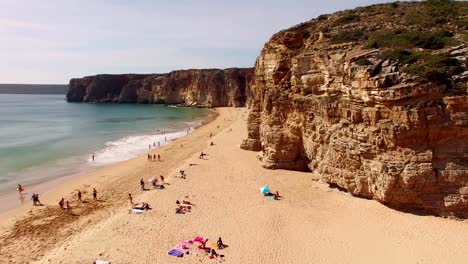 Group-of-people-resting-on-beach-in-Portugal,-Praia-do-Beliche,-Sagres,-aerial-view
