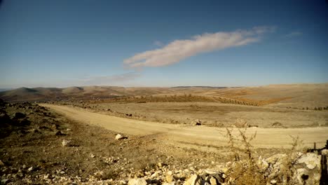 die-unbefestigte-Straße-geht-in-die-Berge-in-der-Ferne,-Gebekli-Tepe,-der-Wüste,-im-Osten-der-Türkei,-die-Grenze-zu-Syrien