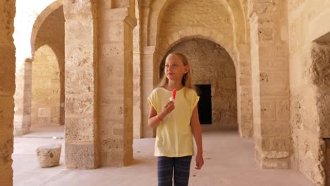 Junge-Mädchen-gehen-und-essen-Eis-auf-Hintergrund-mit-Bogen-aus-Beige-Steinen