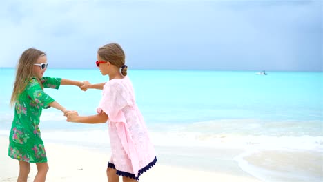 Two-little-happy-girls-have-a-lot-of-fun-at-tropical-beach-playing-together