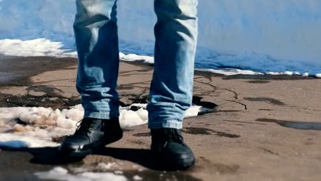 Man-falls-into-a-snow-puddle-in-the-asphalt-with-his-foot.-Close-up-legs.