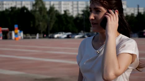 brunette-woman-in-the-street-is-dropping-a-phone-while-talking