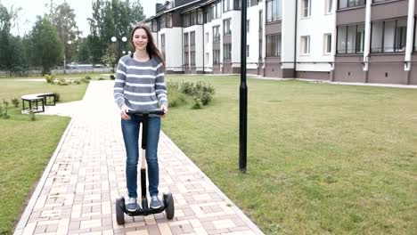 Schöne-Brünette-Frau-rollt-auf-Gyro-Roller-in-der-Nähe-des-Hauses.