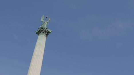 The-Millennium-Monument-on-Heroes-square-and-Hungarian-capital-city-of-Budapest-tilting-4K-2160p-UltraHD-footage---Hosok-ter-statues-by-the-day-in-front-of-blue-sky-4K-3840X2160-UHD-tilt-video