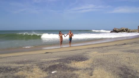 SLOW-MOTION:-Smiling-couple-running-along-the-sunny-beach