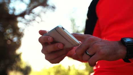 Ciclista-de-montaña-en-sosteniendo-un-teléfono-inteligente-con-el-seguimiento-de-la-aplicación