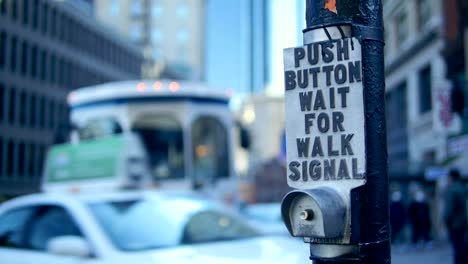 Boston-Crosswalk-Button-with-Trolly,-Traffic-and-Pedestrians-in-Bokeh