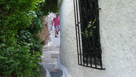 Un-solo-hombre-caminando-a-estrechas-calles-de-Plaka,-Atenas,-Grecia