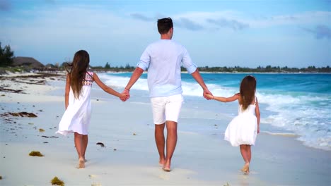 Family-walking-on-white-beach-on-caribbean-island-in-the-evening