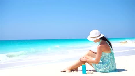 Junge-Frau-Creme-auf-ihre-glatte-gebräunte-Beine-am-tropischen-Strand