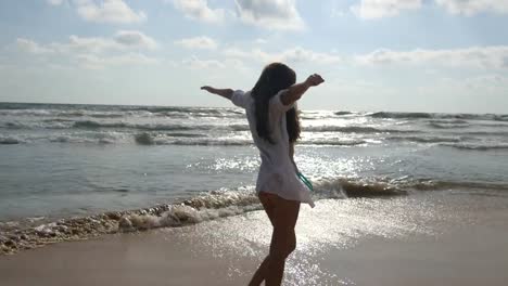 Mujer-feliz-en-bikini-y-camiseta-caminando-en-el-agua-de-mar-en-la-playa.-Joven-hermosa-chica-disfrutando-de-la-vida-y-la-diversión-a-la-orilla-del-mar.-Vacaciones-de-verano-o-vacaciones