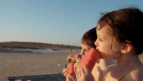 Three-kids-eating-watermelons-at-the-beach