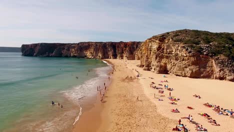 People-rest-on-a-beautiful-sandy-beach-in-Portugal,-Praia-do-Beliche,-Sagres,-aerial-view