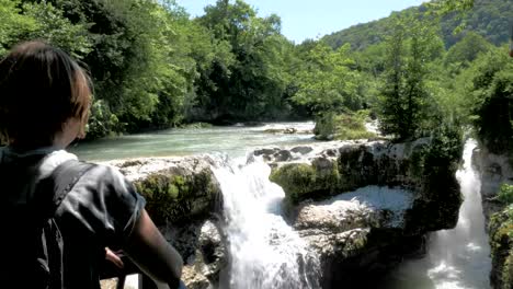 Junges-Mädchen-schaut-zu-dem-kleinen-Wasserfall,-Georgia,-Martvili