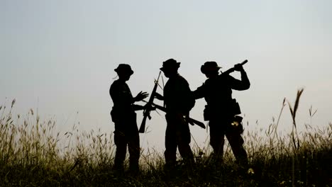 Silhouette-von-drei-voll-ausgestattet-und-bewaffnete-Soldaten-stehen-in-Schlachtfeld-nach-dem-Ende-des-Krieges.