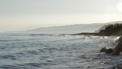 Sea-waves-breaking-against-the-rocks-and-muslim-man-praying-the-Quran-at-sunset