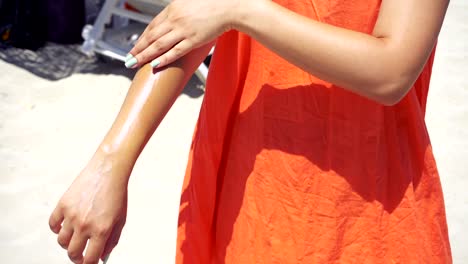 Mujer-de-separarse-de-protector-solar-en-el-brazo-en-la-playa-en-un-día-soleado-caliente