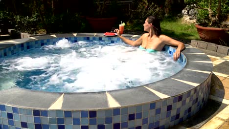 A-woman-relaxes-in-a-hot-tub-and-eats-a-watermelon