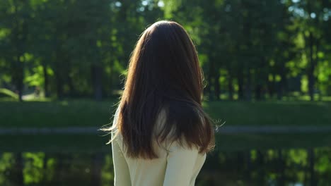 Mujer-tapa-su-pelo-largo-brillante-contra-un-follaje-verde