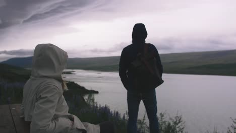 Young-couple-with-enjoying-view-of-stromy-clouds-over-the-lake,-cinematic-shot