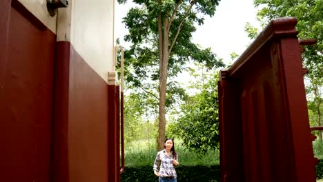 4K-video.-happy-Asian-tourist-woman-at-railway-station,-wave-hand-for-say-hello-to-friend,-walk-to-the-train-and-step-up-on-stair.-travel-in-Asia-by-vintage-train.-leisure-tourist-travelling-by-train