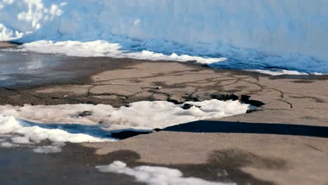 Mann-fällt-in-eine-Pfütze-von-Schnee-in-den-Asphalt-mit-seinem-Fuß.-Close-up-Beine.