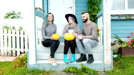 Three-people-in-background-of-village-house-on-farm-speak-and-laugh.