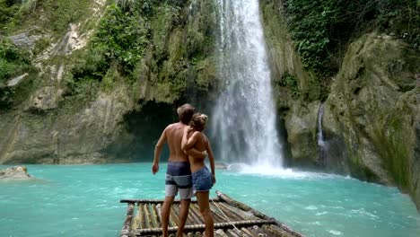 Young-couple-being-affectionate-at-beautiful-tropical-waterfall-in-the-Philippines-enjoying-vacations-and-freedom.-People-travel-love-concept