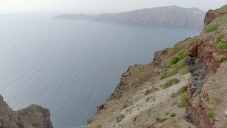 Vista-aérea-mujer-caminando-en-el-techo-de-la-casa-tradicional-de-Santorini,-Grecia.