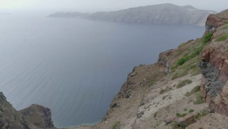 Luftbild-Frau-steht-am-Rand-des-Daches-auf-Santorini-traditionellen-Haus.