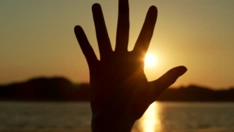 Silhouette-Of-Woman-Making-Flare-Shape-With-Hands-Against-Sun