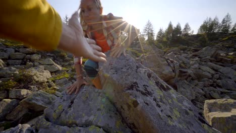 Teammate-helping-hiker-to-reach-summit.-Couple-hiking-in-Switzerland,-hand-reach-out-to-help-female-hiker-reach-the-summit.-A-helping-hand-concept