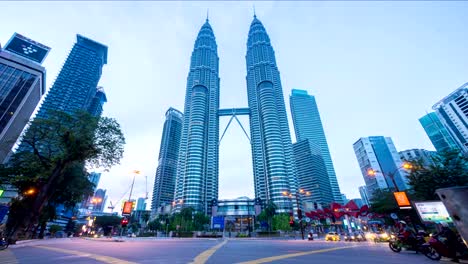 Night-to-day-4k-time-lapse-of-junction-traffic-light-in-front-of-Suria-KLCC-with-Petronas-Towers.