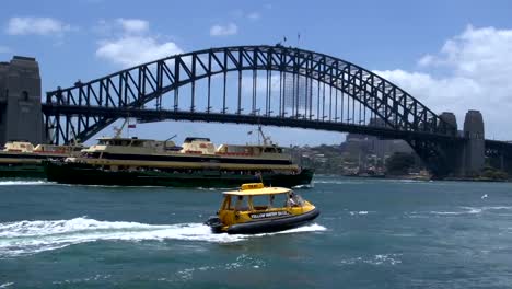 Big-ferries-and-a-small-water-taxi-passing-by-harbour-bridge-in-Sydney