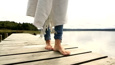 Close-up-on-woman's-feet-standing-on-jetty-above-lake