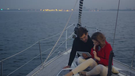 Couple-is-using-tablet-on-a-yacht-in-the-sea.