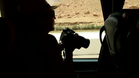 Mujer-joven-mirando-y-tomando-fotos-a-través-de-la-ventana,-sentado-en-los-asientos-traseros-en-autobús-en-carretera-tripg-mujer-mirando-a-través-de-la-ventana-y-jugando-con-las-manos-sentados-en-los-asientos-traseros-en-autobús-en-viaje