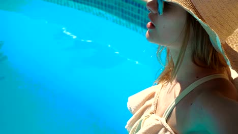 a-young-girl-wearing-a-hat-and-glasses-stands-in-a-swimsuit-in-pool-water