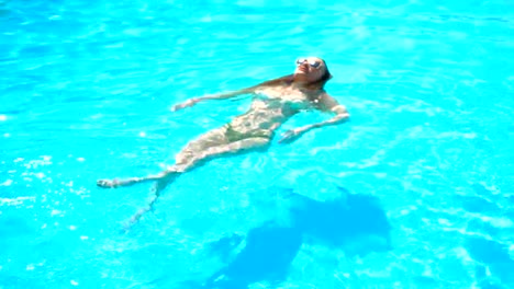 Junge-Mädchen-in-Gläsern-schwimmt-auf-dem-Rücken-in-einem-blauen-pool