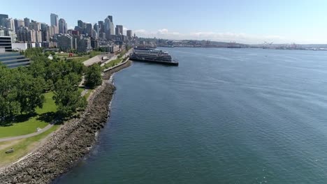 Aerial-of-Waterfront-City-Park-with-Piers-and-Downtown-City-Skyscraper-Buildings-in-Background