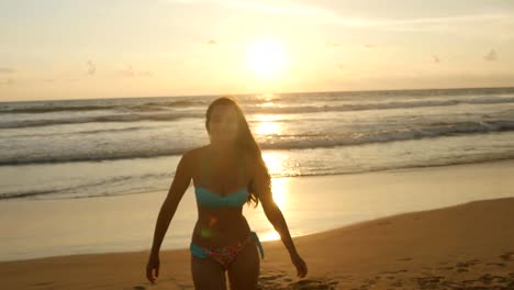 Beautiful-young-woman-in-bikini-standing-near-the-sea-on-sunset.-Attractive-sexy-girl-with-long-hair-posing-on-the-ocean-shore-at-sunrise.-Female-on-the-beach-enjoying-life-during-vacation.-Close-up