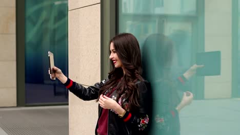 Girl-with-tablet-stands-leaning-against-glass-wall