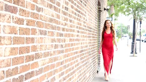 Young-woman-in-red-dress-walking-into-focus-in-urban-scene