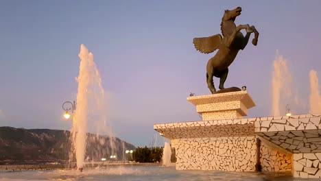 Korinth,-Griechenland,-5.-Oktober-2017.-Zentraler-Platz-von-Korinth-in-Griechenland-mit-Pegasus-Statue-gegen-einen-wunderschönen-Sonnenuntergang.