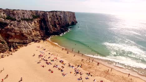 Beautiful-cliffs-and-sandy-beach-with-resting-people-in-Portugal,-Praia-do-Beliche,-Sagres-aerial