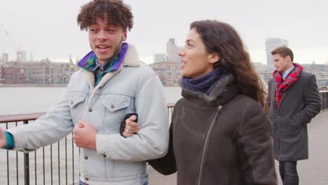 Friends-Walking-Along-South-Bank-On-Winter-Visit-To-London