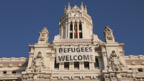 Bandera-de-refugiados-Bienvenido-a-la-fachada-de-Palacio-de-comunicaciones-con-Madrid