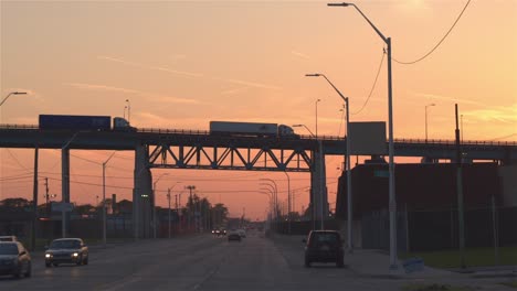 CLOSE-UP:-Silhouette-Autos-fahren-auf-stark-frequentierten-Autobahn-in-der-industriellen-Stadt-bei-Sonnenuntergang