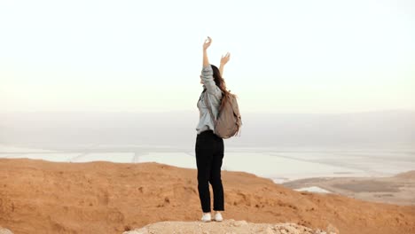 Girl-at-mountain-view,-jumping-with-arms-wide-open.-Pretty-European-woman-happy-and-excited.-Happiness.-Israel-desert-4K